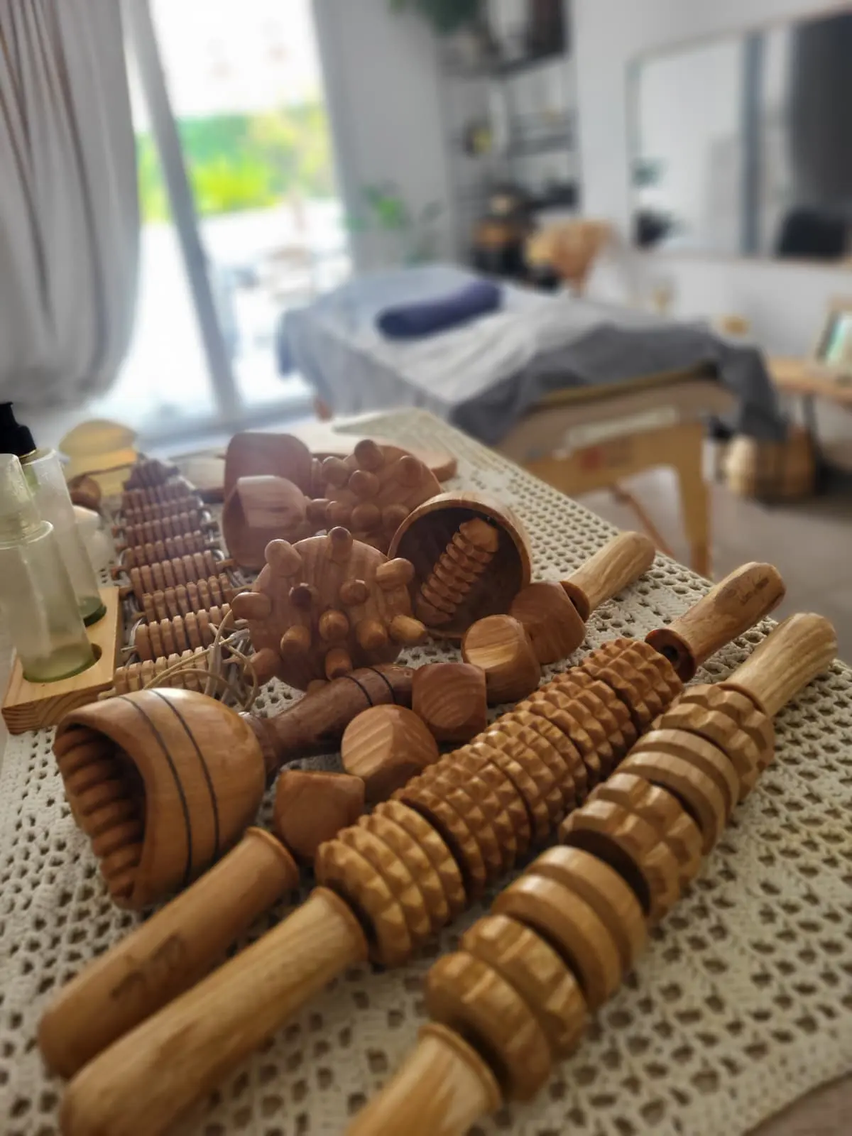 La cabine de Madero Sud : table de soin, outils de madérothérapie en bois posés sur un napperon au crochet, lumière naturelle.