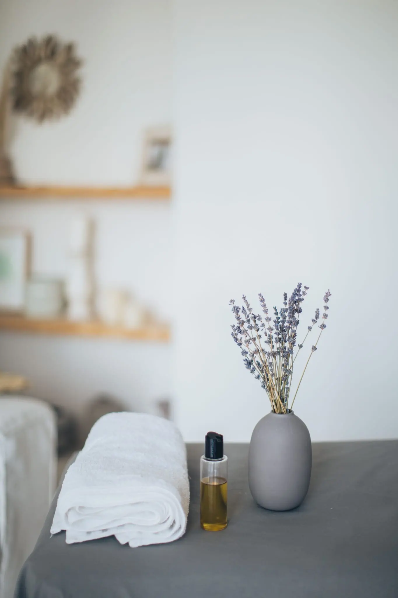 Espace de soin épuré : serviette roulée, flacon d'huile et bouquet de lavande.